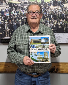 Obie Carl, President of the Harrisonville Chamber Foundation, holding up a copy of the Looking Back Book.